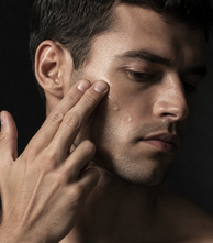 Close-up of fingertips working product into a man's cheek