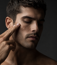 Man smoothing cream along his cheekbone
